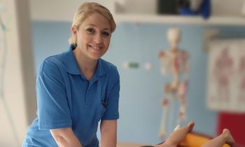 Julia Silberbauer demonstriert eine physiotherapeutische Behandlung an einer Patientin in einem Behandlungsraum.