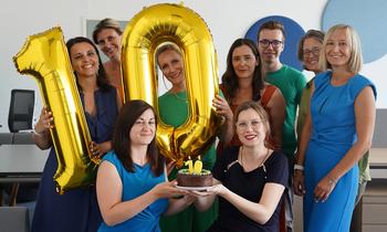 Ein fröhliches Team der FH Burgenland Weiterbildung hält goldene Ballons mit der Zahl 10 – Symbol für ein Jahrzehnt erfolgreicher Weiterbildung und über 6.000 engagierte Studierende.