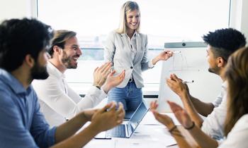 Junge Frau präsentiert an Flipchart vor motiviertem Team – symbolisiert erfolgreiche Führung durch Veränderungsprozesse im MBA-Programm Change Management und Leadership der FH Burgenland.