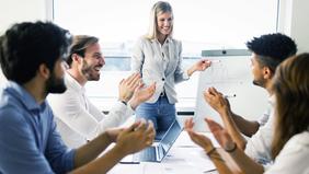 Junge Frau präsentiert an Flipchart vor motiviertem Team – symbolisiert erfolgreiche Führung durch Veränderungsprozesse im MBA-Programm Change Management und Leadership der FH Burgenland.