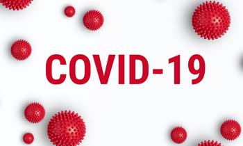 Grafik mit dem Schriftzug „COVID-19“ in großen roten Buchstaben. Rundherum sind stilisierte rote Virenpartikel abgebildet, die das SARS-CoV-2-Virus symbolisieren. Die Darstellung verweist auf eine eingeschränkte Präsenz aufgrund der Pandemie.