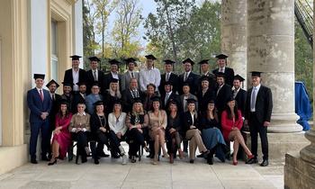 Gruppenfoto von Absolventinnen und Absolventen vor einem historischen Gebäude, feierliche Sponsion der FH Burgenland.