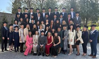 Sponsion Hochschule Burgenland Gruppe von Absolvent*innen mit Sponsionshüten lächelt in die Kamera im Schlossgarten von Schloss Esterházy.