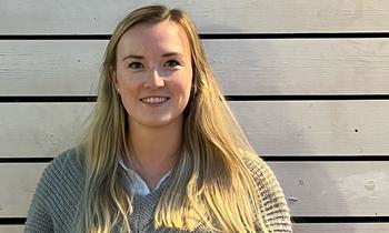 Alexandra van Bracht, MBA-Studierende der FH Burgenland, mit blondem Haar und grauem Strickpullover, lächelt in die Kamera.