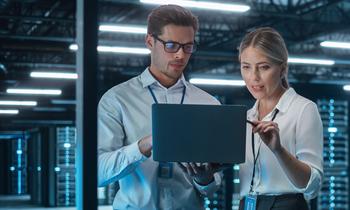 Diploma of Advanced Studies in Informationssicherheit und IT-Risikomanagement Zwei IT-Fachkräfte in einem modernen Serverraum analysieren gemeinsam Daten auf einem Laptop – Symbolbild für Informationssicherheit und IT-Risikomanagement im Rahmen des neuen Weiterbildungsprogramms der FH Burgenland.