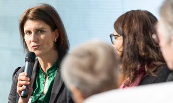 Bettina Schauer-Frank, Lehrgangsleitung AIM, spricht bei einer Podiumsdiskussion im Rahmen der AQ Austria Jahrestagung 2022 in Wien in ein Mikrofon, flankiert von weiteren Teilnehmerinnen.