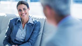 Junge Businessfrau im Gespräch mit einem Mann, freundlich lächelnd – Symbol für professionelle Kommunikation, Rechtsberatung und wirtschaftliches Know-how.
