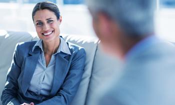Junge Businessfrau im Gespräch mit einem Mann, freundlich lächelnd – Symbol für professionelle Kommunikation, Rechtsberatung und wirtschaftliches Know-how.