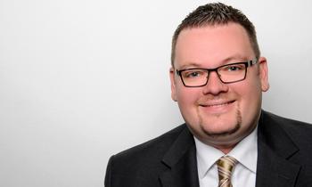 Porträt von Marc Schachteli im Anzug mit hellem Hintergrund, MBA-Absolvent der FH Burgenland