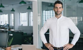 Selbstbewusster junger Mann in modernem Büro – steht sinnbildlich für innovative Führungskompetenz im Rahmen des MBA Agiles Management der FH Burgenland.