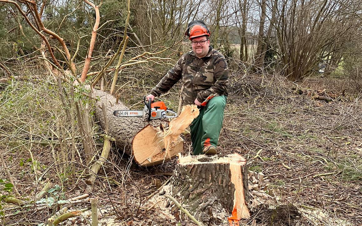 Marc Schachteli beim Bäumefällen im Wald mit Motorsäge, trägt Schutzkleidung und Helm