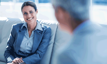 Business-Frau im Gespräch mit einer anderen Person in moderner Büroumgebung – symbolisiert rechtliche und wirtschaftliche Beratung im Rahmen des MBA Wirtschaftsrecht der FH Burgenland.