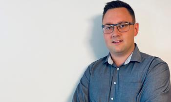 Michael Prodinger steht mit verschränkten Armen vor einer hellen Wand und blickt selbstbewusst in die Kamera.