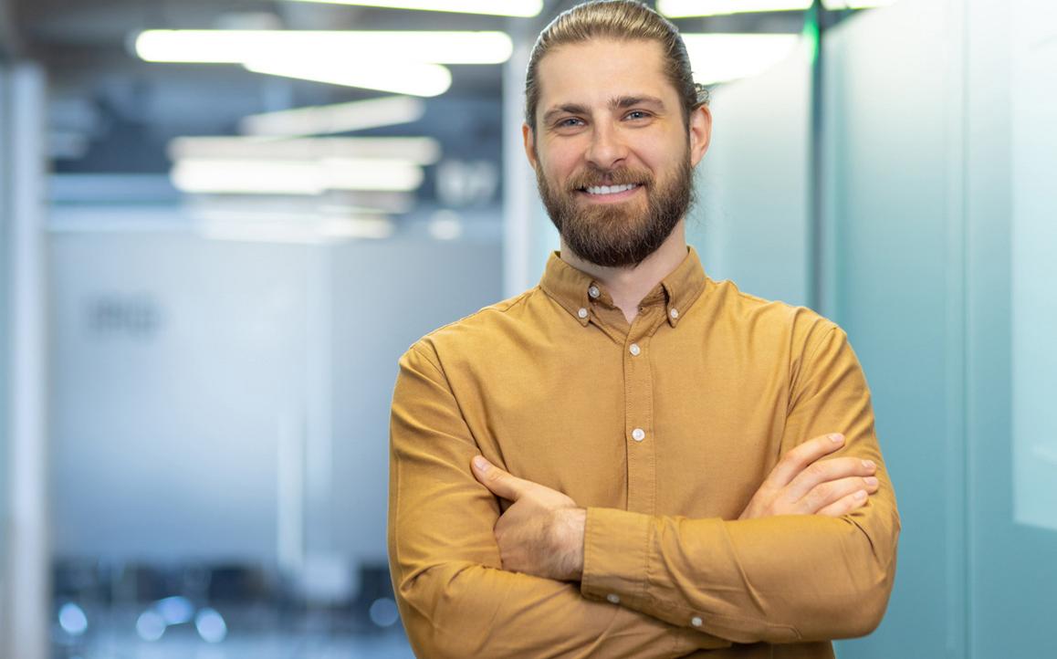 Selbstbewusster Mann mit verschränkten Armen in modernem Arbeitsumfeld – steht für praxisnahe Spezialisierung und digitale Weiterbildung im Bildungsbereich.