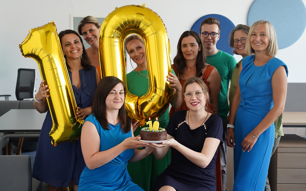 Ein fröhliches Team der FH Burgenland Weiterbildung hält goldene Ballons mit der Zahl 10 – Symbol für ein Jahrzehnt erfolgreicher Weiterbildung und über 6.000 engagierte Studierende.