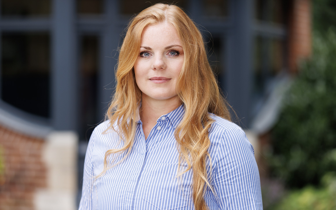 Maxi Müller im Business-Outfit vor einem modernen Bürogebäude. Das Bild vermittelt Professionalität und symbolisiert ihren akademischen Weg im Fernstudium.