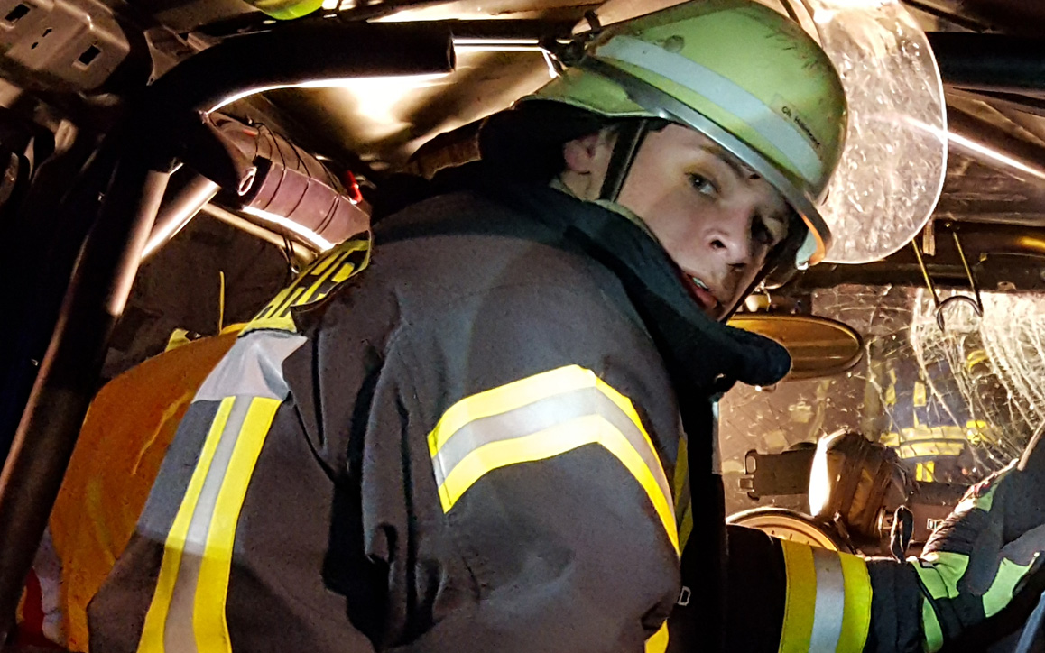 Christopher Hillebrand in kompletter Feuerwehrmontur im Einsatzfahrzeug – Engagement in der Freiwilligen Feuerwehr.