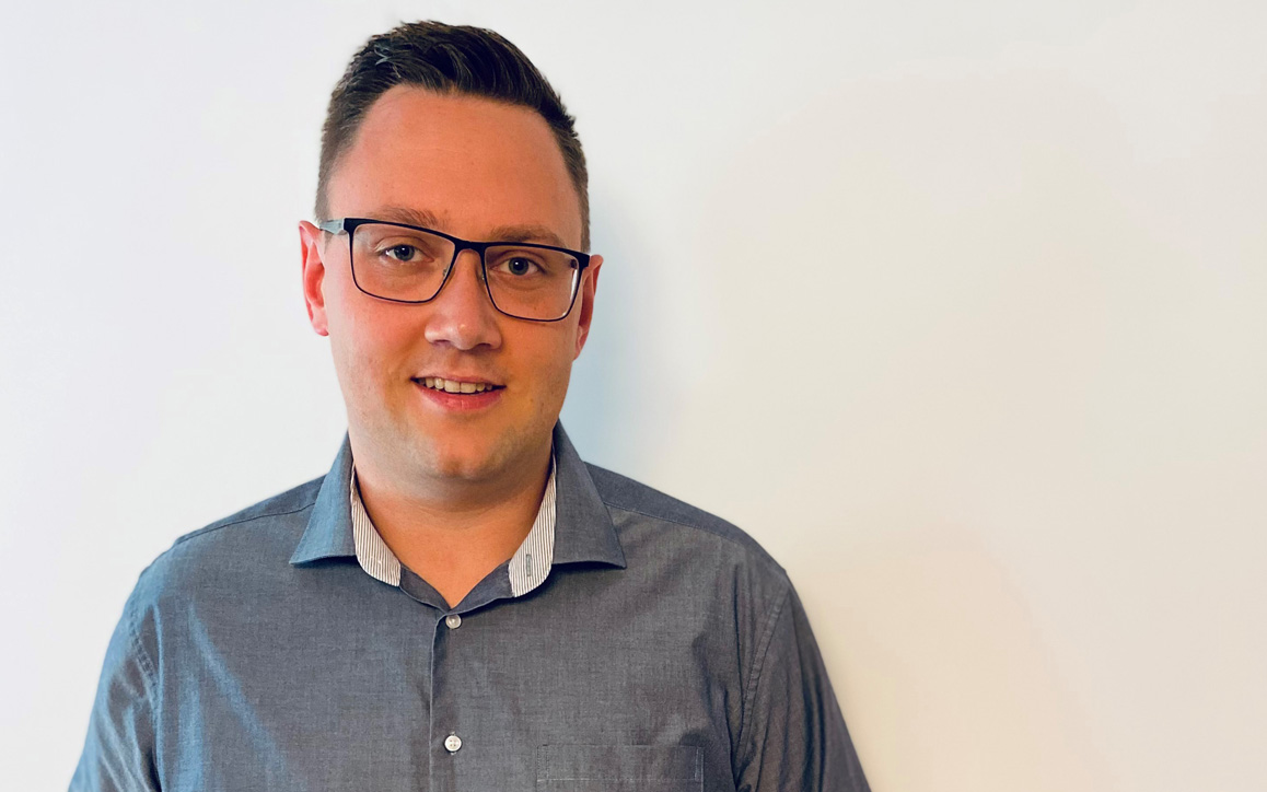 Michael Prodinger vor einer weißen Wand mit Brille und grauem Hemd. Über dem Bild ist ein Zitat eingeblendet, das die Stärke des Netzwerks im Fernstudium betont.