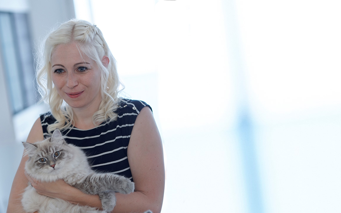 Manuela Schoyswohl lächelt und hält eine grau-weiße Katze im Arm.