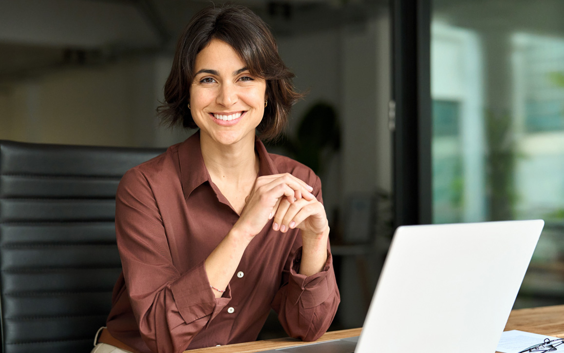 Freundlich lächelnde Frau am Laptop – steht für Kompetenz, digitale Weiterbildung und die neuen ERP-Programme der Hochschule Burgenland.