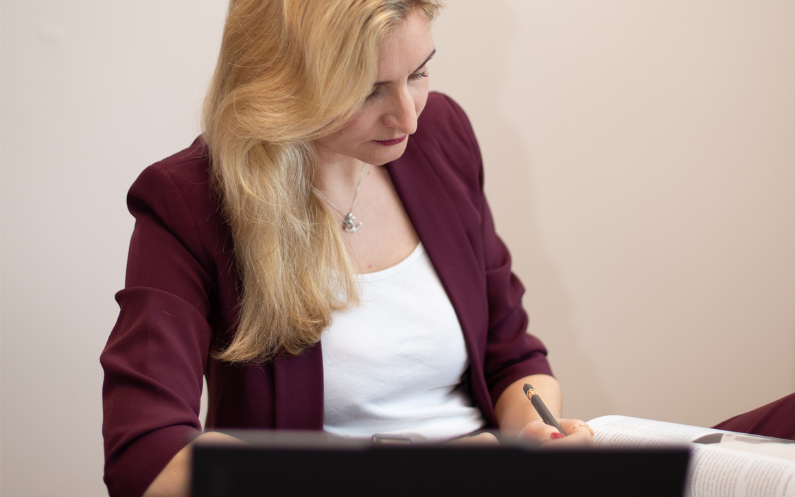 Franziska Gattringer sitzt konzentriert am Schreibtisch und blickt in ihre Unterlagen.