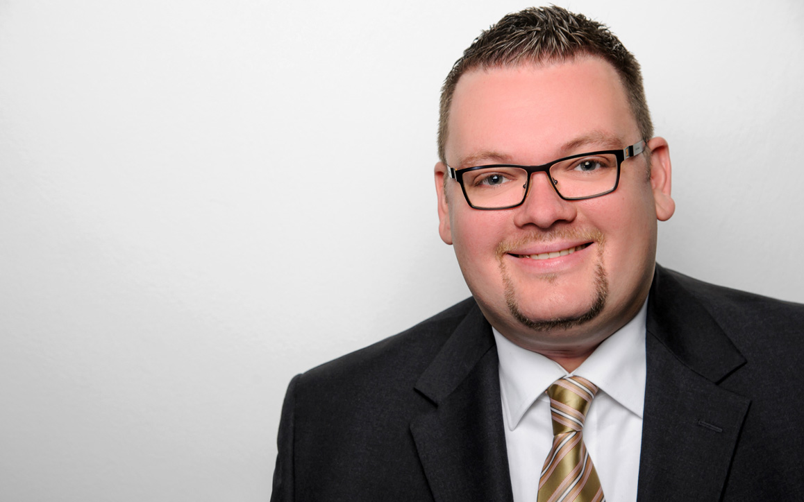 Porträt von Marc Schachteli im Anzug mit hellem Hintergrund, MBA-Absolvent der FH Burgenland